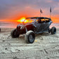 Off-road vehicle on a beach with a sunset in the background