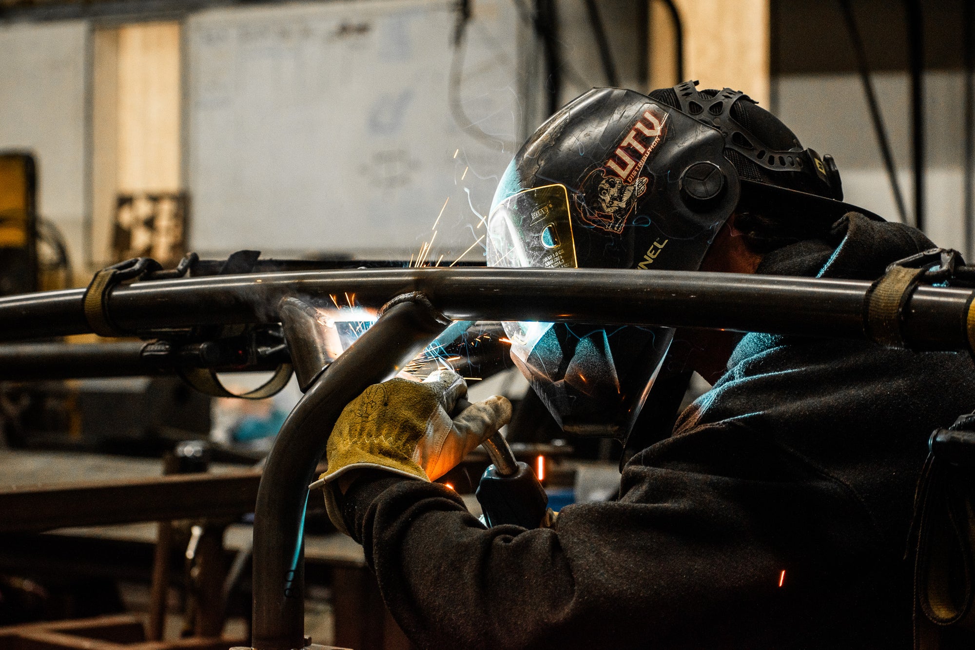 person welding roll cage in a fabrication shop